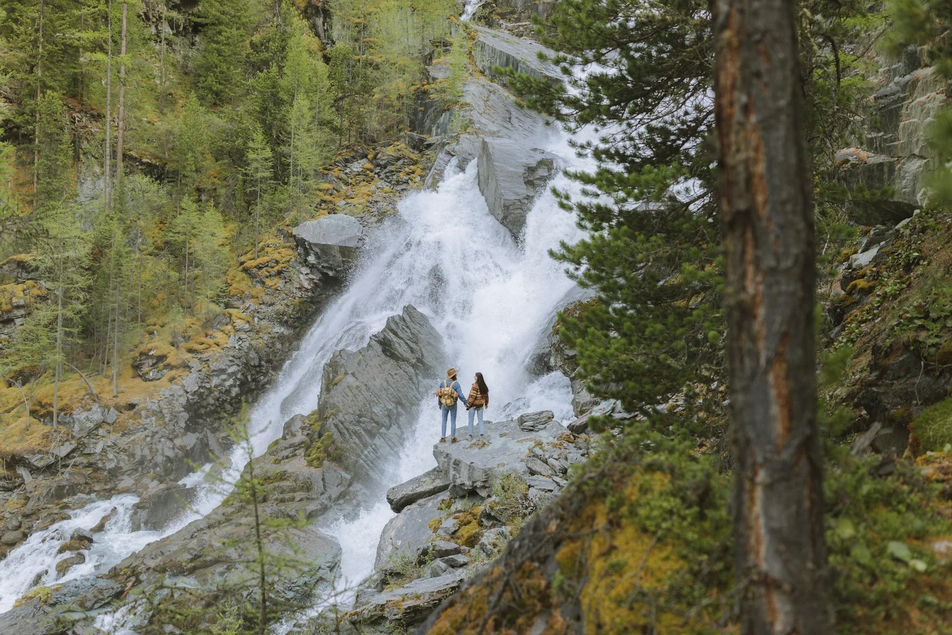 Couple hiking near a waterfall surrounded by lush greenery