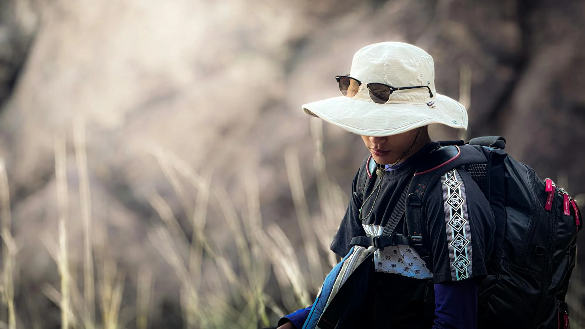 Hiker with sun hat and backpack on a warm-weather trail